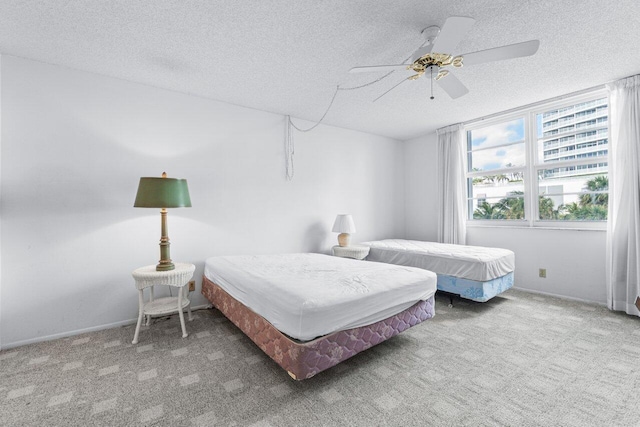 carpeted bedroom featuring ceiling fan and a textured ceiling