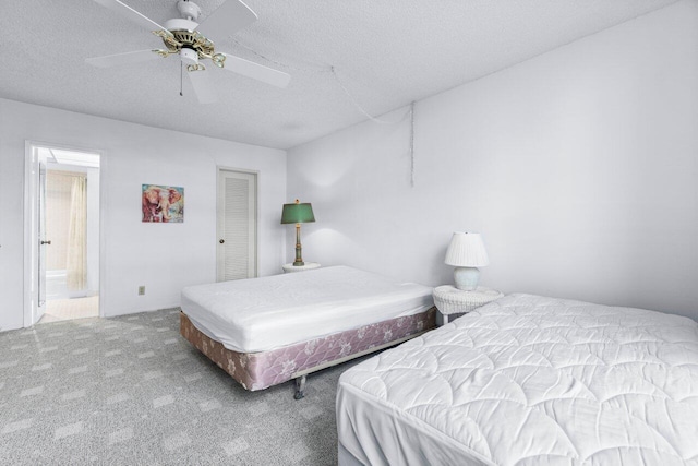 bedroom featuring light carpet, ensuite bathroom, a textured ceiling, ceiling fan, and a closet