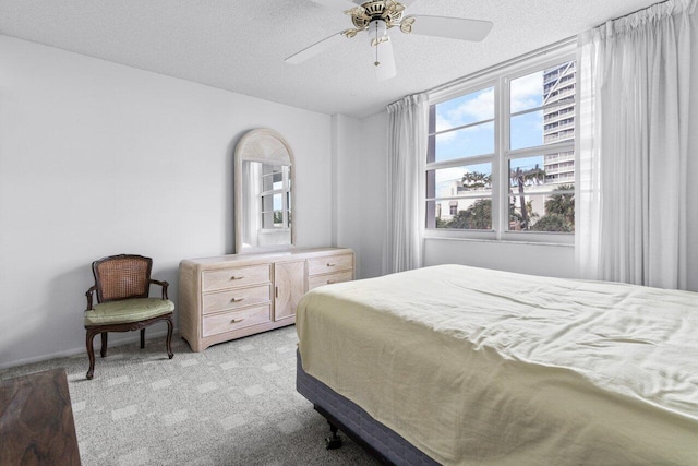 carpeted bedroom featuring ceiling fan and a textured ceiling