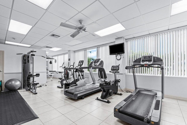 exercise room featuring ceiling fan, a drop ceiling, and light tile patterned floors