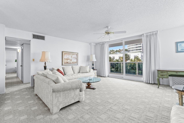 living room featuring light carpet, a textured ceiling, and ceiling fan