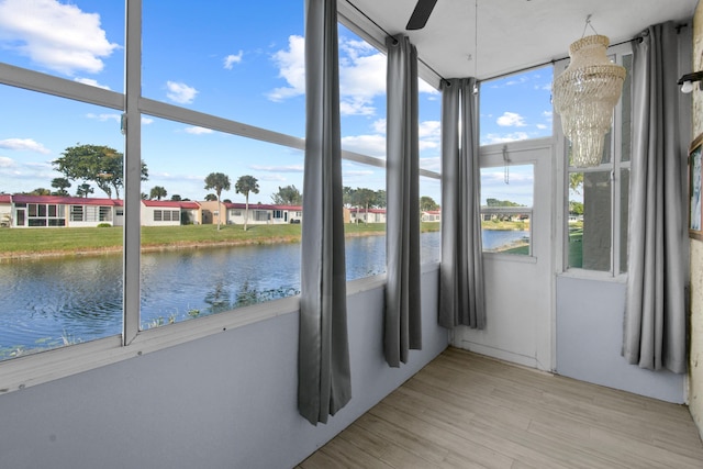 unfurnished sunroom with a water view and ceiling fan with notable chandelier