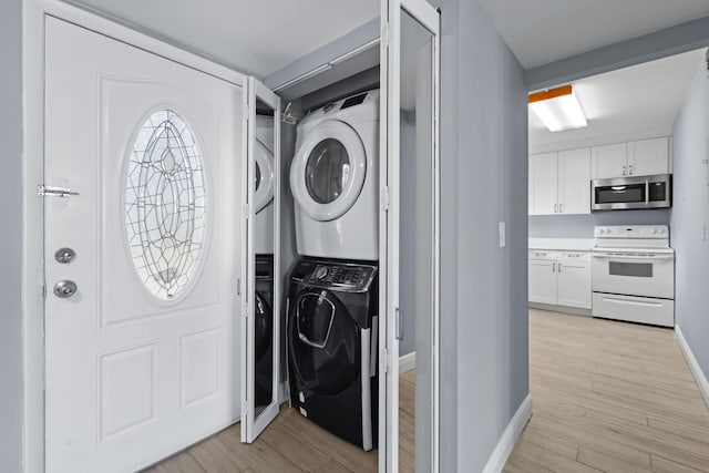 clothes washing area with stacked washing maching and dryer and light wood-type flooring