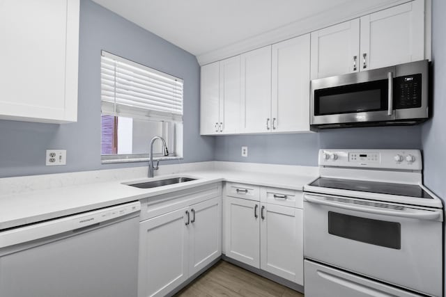 kitchen featuring white cabinetry, white appliances, sink, and light hardwood / wood-style flooring