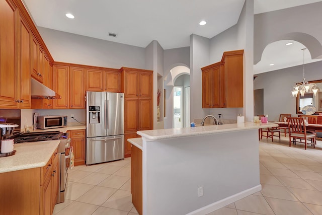 kitchen featuring an inviting chandelier, light tile patterned floors, appliances with stainless steel finishes, decorative light fixtures, and kitchen peninsula