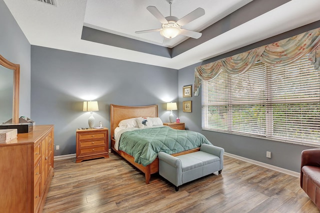 bedroom featuring hardwood / wood-style flooring, ceiling fan, and a raised ceiling