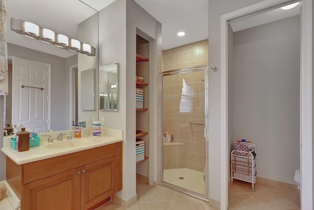 bathroom featuring tile patterned flooring, vanity, a shower with door, and toilet