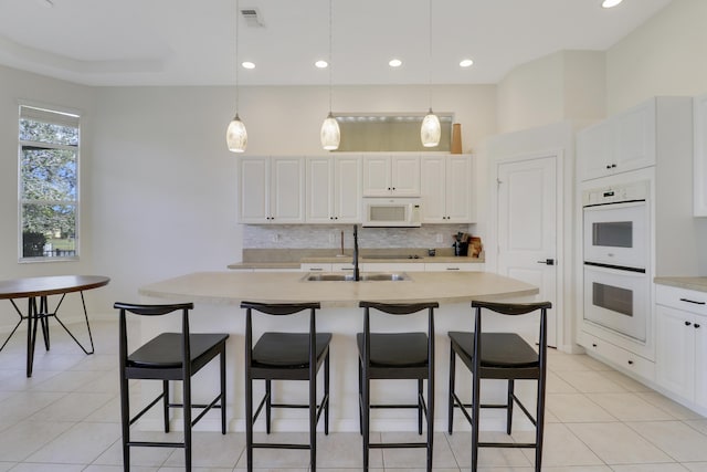 kitchen with a center island with sink, white cabinets, white appliances, and sink