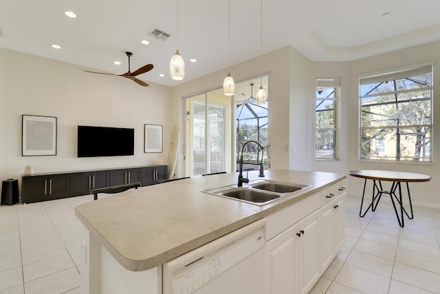 kitchen with white dishwasher, a center island with sink, sink, ceiling fan, and white cabinetry