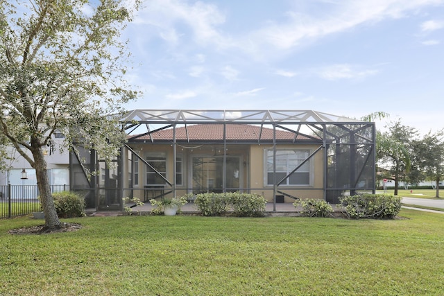 rear view of house with a lanai, ceiling fan, and a lawn