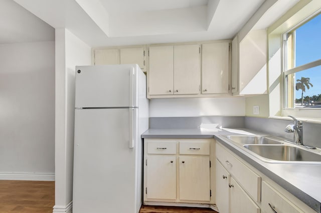 kitchen with white fridge, wood-type flooring, sink, and cream cabinets