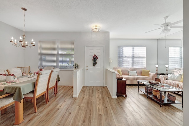 entrance foyer with light wood-type flooring, a textured ceiling, baseboards, and ceiling fan with notable chandelier