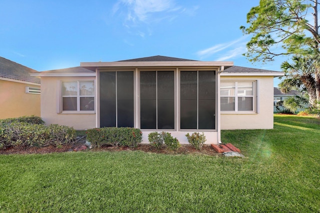 rear view of house featuring a lawn and a sunroom