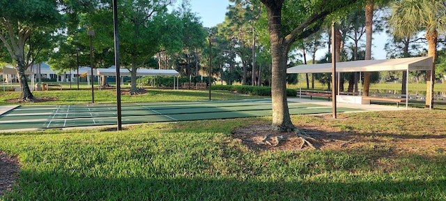 view of community with shuffleboard and a lawn