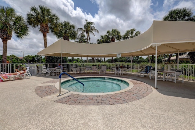 view of swimming pool featuring a community hot tub, fence, and a patio