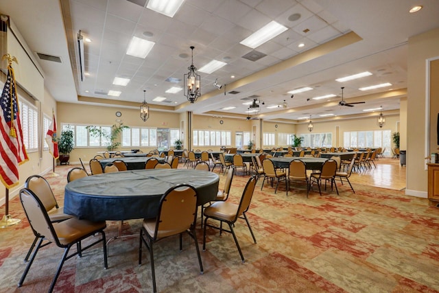 dining space featuring ceiling fan, a drop ceiling, and a tray ceiling