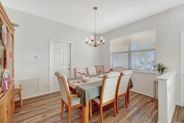 dining area featuring light hardwood / wood-style floors and a notable chandelier