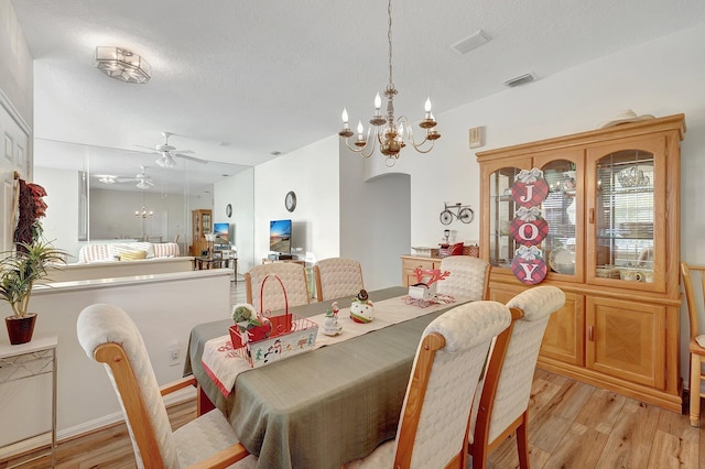 dining room featuring a textured ceiling, light hardwood / wood-style flooring, and ceiling fan with notable chandelier