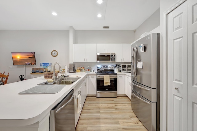 kitchen with white cabinetry, sink, stainless steel appliances, and light hardwood / wood-style floors