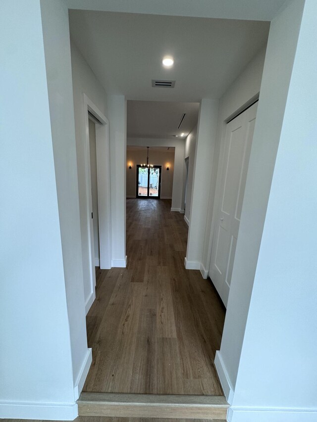 hall featuring hardwood / wood-style floors and an inviting chandelier