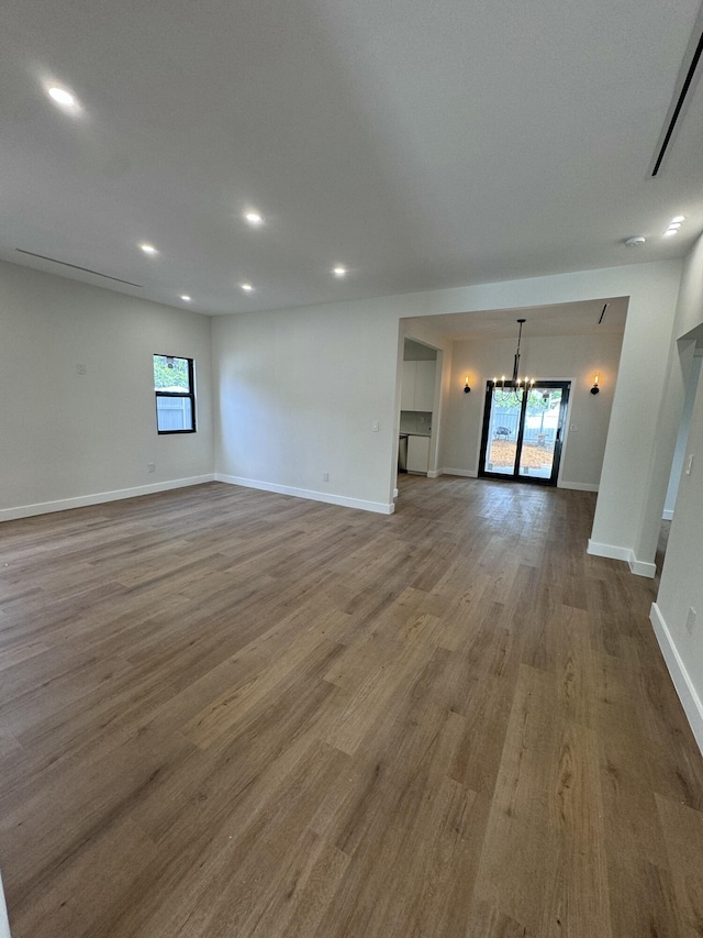 unfurnished living room with a chandelier and hardwood / wood-style floors