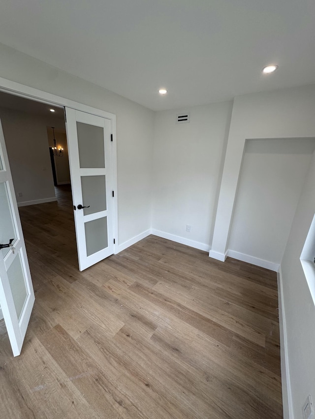 empty room featuring light hardwood / wood-style floors and a notable chandelier