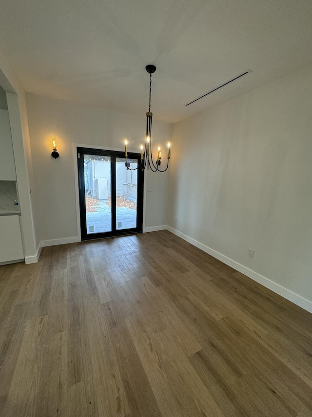 unfurnished dining area featuring hardwood / wood-style flooring and an inviting chandelier