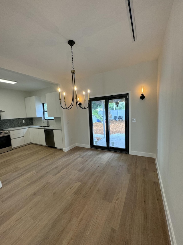 interior space with dishwasher, light hardwood / wood-style flooring, a chandelier, decorative light fixtures, and white cabinets