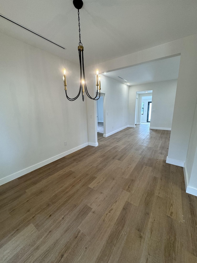 unfurnished dining area with a notable chandelier and wood-type flooring