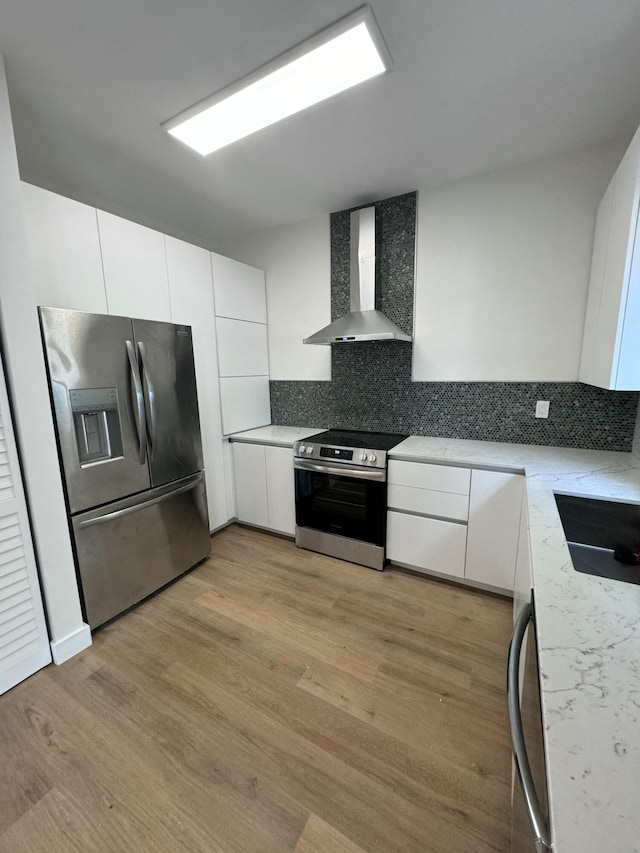 kitchen featuring backsplash, wall chimney exhaust hood, white cabinetry, and stainless steel appliances