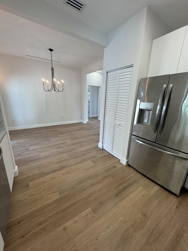 kitchen featuring white cabinets, pendant lighting, stainless steel refrigerator with ice dispenser, and a chandelier