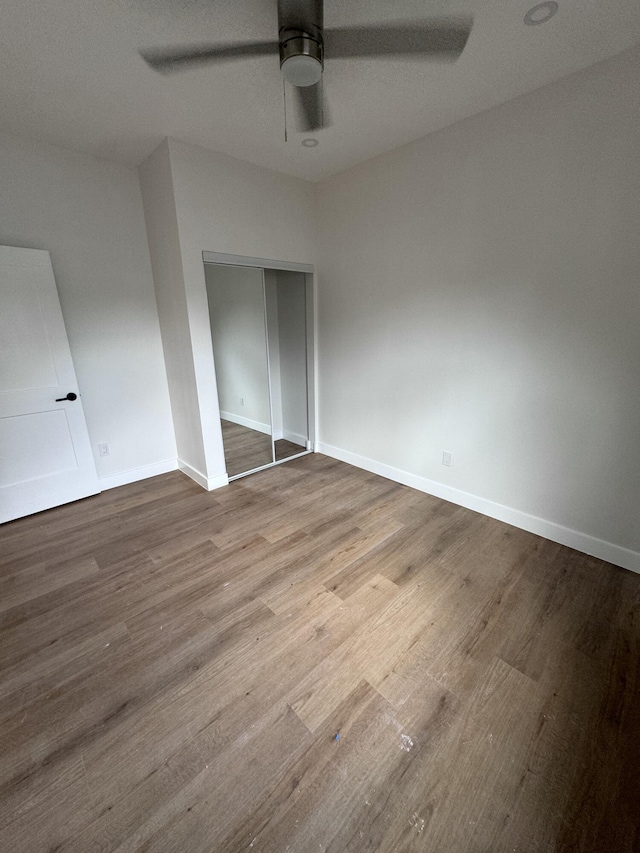 unfurnished bedroom featuring hardwood / wood-style floors, ceiling fan, and a closet