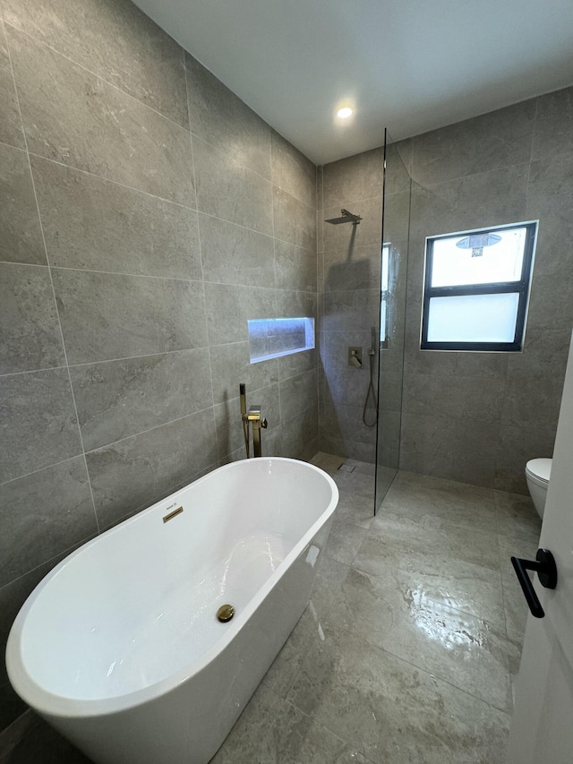 bathroom with toilet, shower with separate bathtub, and tile walls