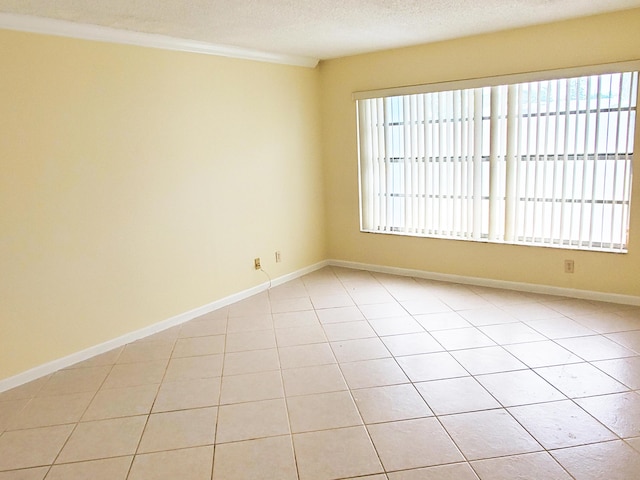 empty room featuring light tile patterned floors, a textured ceiling, and crown molding