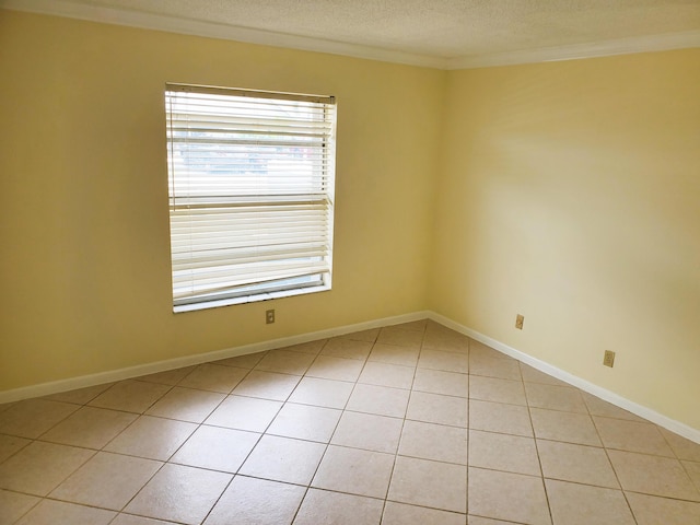 tiled empty room featuring a textured ceiling and crown molding