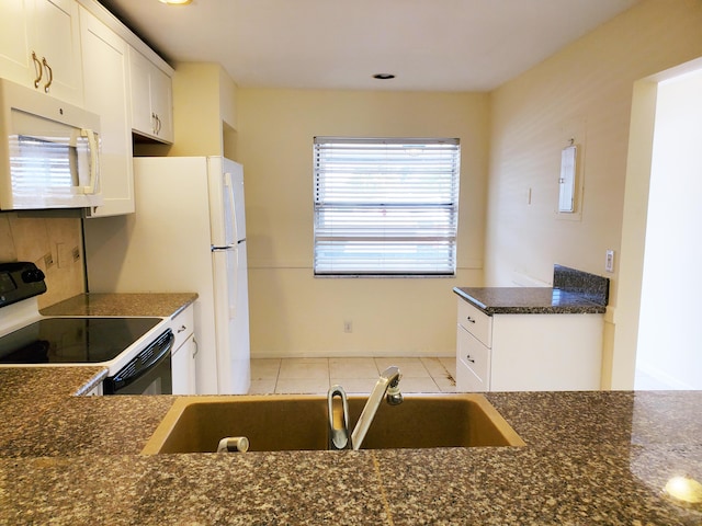 kitchen featuring light tile patterned floors, electric range oven, white cabinetry, and sink