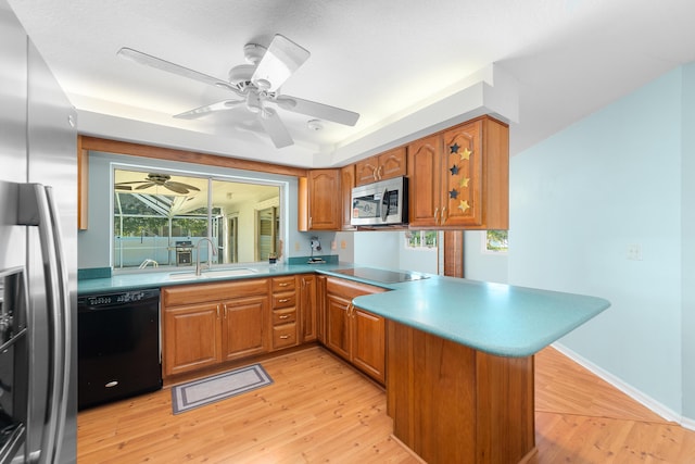 kitchen featuring kitchen peninsula, sink, light hardwood / wood-style flooring, and black appliances