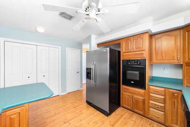 kitchen featuring stainless steel refrigerator with ice dispenser, light wood-type flooring, oven, and ceiling fan