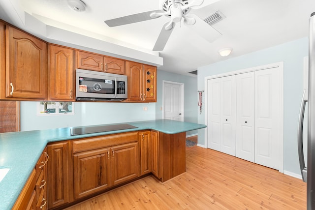 kitchen featuring kitchen peninsula, ceiling fan, black electric stovetop, and light hardwood / wood-style floors