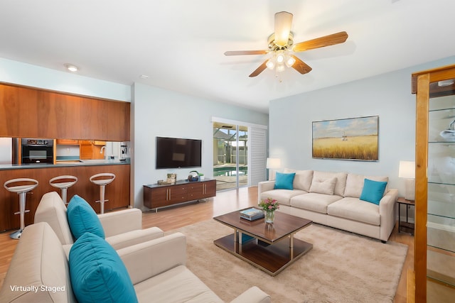 living room featuring ceiling fan, light hardwood / wood-style floors, and sink