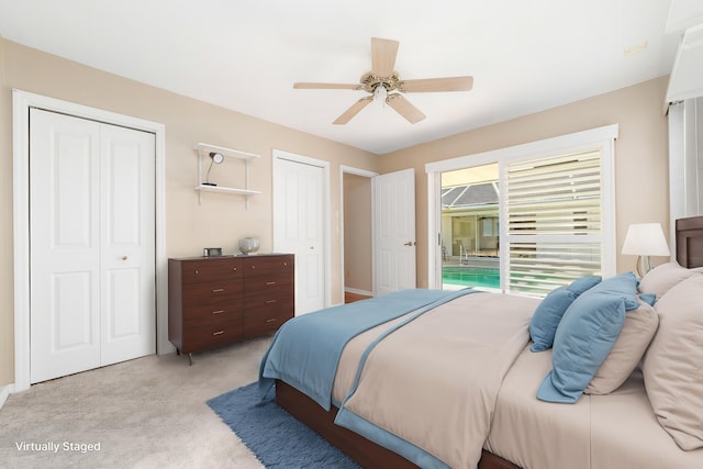 bedroom featuring ceiling fan, light colored carpet, and multiple closets