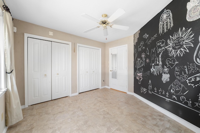 unfurnished bedroom with multiple closets and ceiling fan