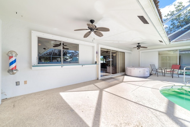 view of patio featuring glass enclosure, ceiling fan, and a hot tub