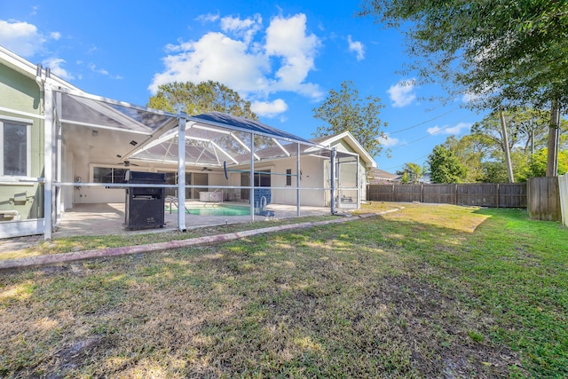 rear view of property with a lawn, glass enclosure, a fenced in pool, and a patio