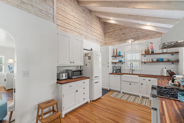 kitchen with butcher block countertops, a healthy amount of sunlight, white cabinetry, and stainless steel appliances