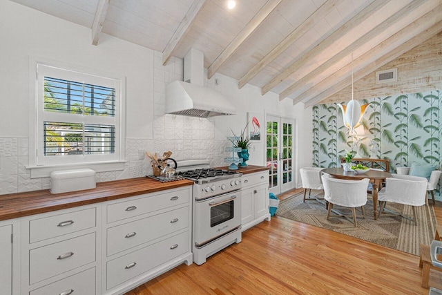 kitchen featuring white cabinetry, hanging light fixtures, wood counters, high end stove, and tile walls