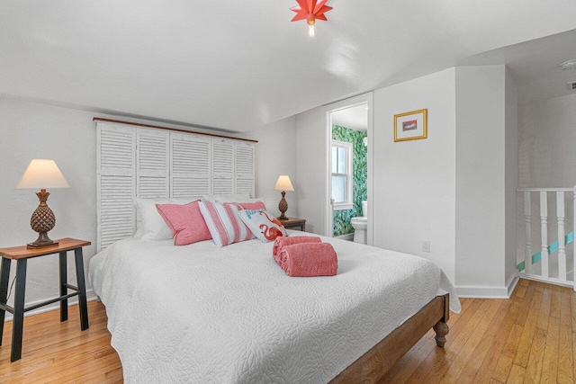 bedroom with connected bathroom and hardwood / wood-style floors