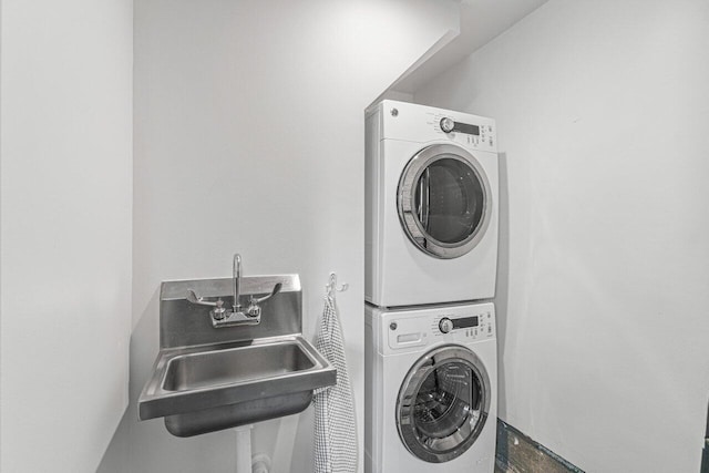 clothes washing area featuring stacked washer and dryer and sink