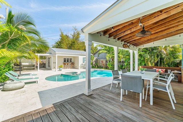 view of swimming pool featuring an in ground hot tub, an outbuilding, ceiling fan, and a deck