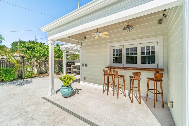 view of patio / terrace with ceiling fan, a bar, and a pergola